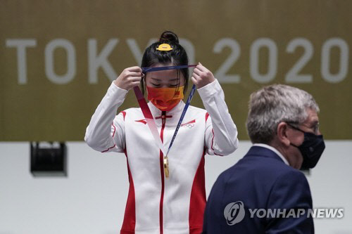 양첸(중국)이 24일 도쿄올림픽 여자 10ｍ 공기소총 결선에서 우승한 후 토마스 바흐 IOC 위원장으로부터 금메달을 건네받아 목에 걸고 있다.   연합뉴스